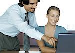 Businessman helping female colleague with computer