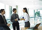 Three office workers standing with cups of coffee, talking