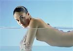 Nude woman doing lastone therapy in water, looking at camera