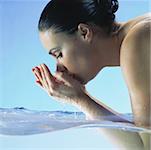 Woman in water cupping hands to face