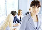 Businesswoman smiling at camera, meeting in background