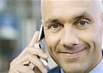 Businessman using cell phone, smiling