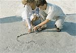 Couple drawing heart in sand
