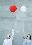 Two children holding balloons and making faces