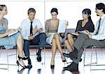 Businesspeople sitting in chairs having meeting, full length