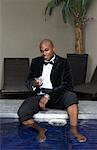 Man in Tuxedo with Feet in Pool Drinking Cocktail