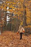 Fille se promener à travers les feuilles de l'automne