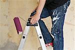 Man on stepladder with paint roller