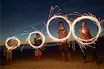 Enfants sur la plage avec des feux de Bengale