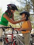 Mother putting bicycle helmet on girl