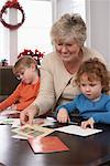 Femme écrivant des cartes de Noël avec les petits-enfants