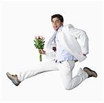 Portrait of a young man jumping and holding a bunch of flowers