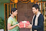 Side profile of a mid adult man giving a gift box to a young woman