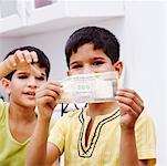 Portrait of a boy holding an Indian five hundred rupee note with his brother taking it