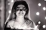 Portrait of a mid adult woman holding oil lamps in a plate and smiling