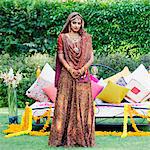 Portrait of a bride in a traditional wedding dress standing in front of a bed on the lawn