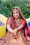 Bride in a traditional wedding dress sitting on the bed and smiling