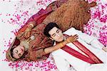 High angle view of a newlywed couple in traditional wedding outfits sleeping on the bed
