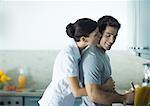 Woman kissing man from behind in the kitchen