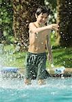 Boy standing in swimming pool, splashing