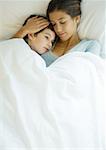 Woman and child lying under covers together