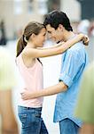 Teen couple standing with foreheads together and arms around each other