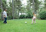 Mature man playing soccer with granddaughter