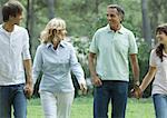 Mature couple walking, holding hands with teen grandchildren