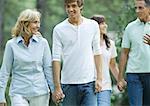 Mature couple walking, holding hands with teen grandchildren