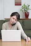 Frau sprechen auf Handy, Laptop-Computer verwenden
