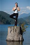 Femme faisant du Yoga sur une souche d'arbre
