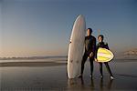 Père et fils à la plage avec des planches de surf