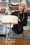 Woman Putting Lightbulb in Lamp in Furniture Store