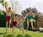 People Jumping Through Sprinkler