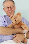 Man in Hospital Bed, Holding Teddy Bear