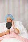 Woman in Hospital Bed, Looking at Mirror