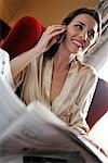 Woman in Hotel with Cellular Phone and Newspaper