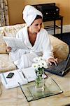 Woman in Bathrobe with Paperwork and Laptop Computer