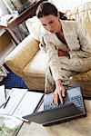 Woman in Bathrobe with Paperwork and Laptop Computer