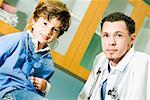 Bildnis eines Knaben mit einem Stethoskop und einem männlichen Arzt neben ihm seinen Herzschlag hören