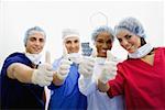 Portrait of a male surgeon and three female surgeons making Thumbs Up sign