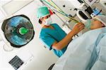 Male surgeon putting an oxygen mask on the mouth of a female patient