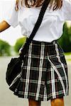 Mid section view of a schoolgirl walking on the road