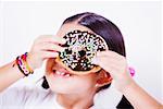 Close-up of a girl holding a donut in front of her eye