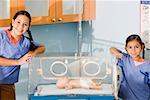 Portrait of two girls standing near an incubator