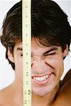 Gros plan d'un homme adult moyen tenant un ruban à mesurer en face de son visage