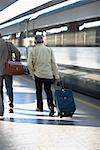 Rear view of two men walking at a railroad station, Rome, Italy