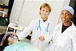 Junge Arzt nachahmen und Anpassen der Sauerstoffmaske eines Patienten mit einer Ärztin, die neben ihm stehend