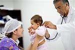 Voir le profil d'une femme médecin jouant avec une petite fille et un médecin de sexe masculin examinant son côté