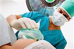 Männliche Chirurgen setzen eine Sauerstoffmaske auf einer Patientin